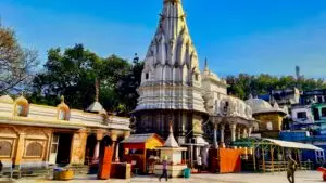 White stone shikhara of Brajeshwari Devi temple rising above a paved courtyard in Kangra