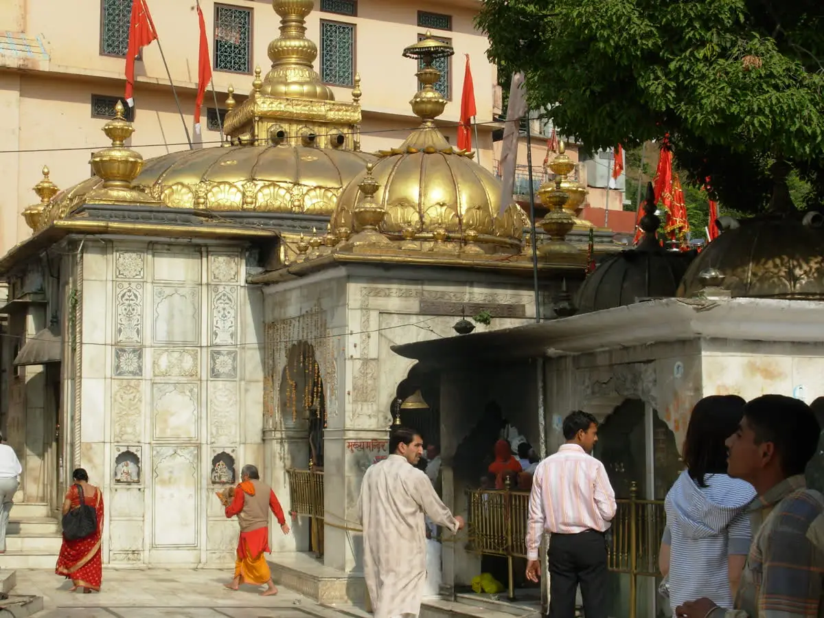 Pilgrims walking past the gilded domes and carved white marble walls of Jwalamukhi temple