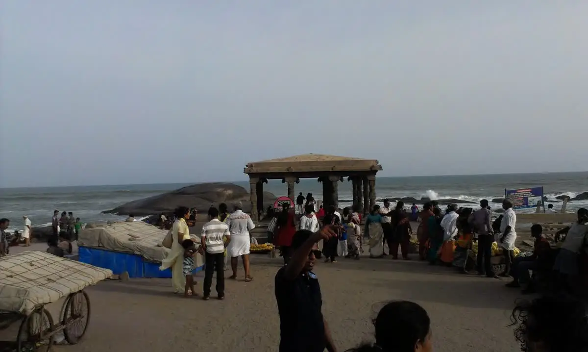 Pilgrims on the beach beside a stone mandapam on the shore at Kanyakumari