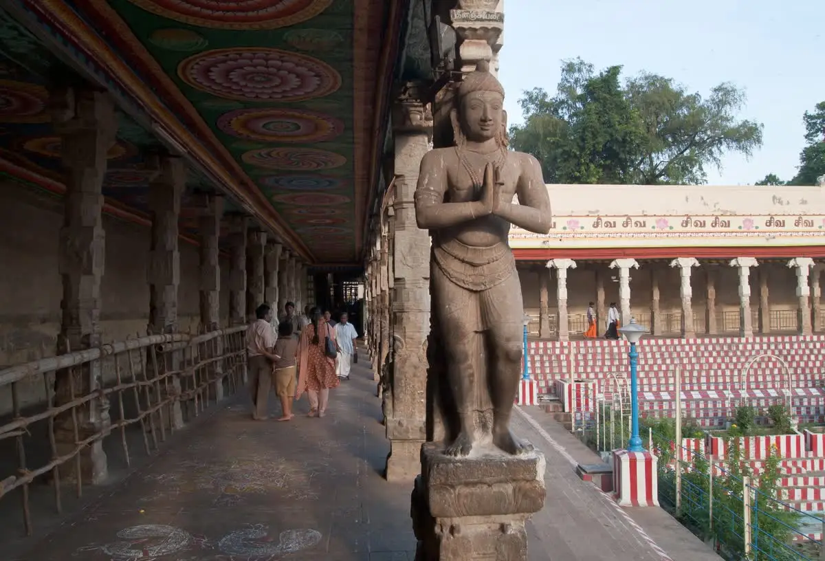 Pillared corridor of Meenakshi Amman temple with a carved figure and painted ceiling beams