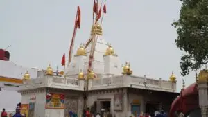 White marble Naina Devi temple with golden finials and pilgrims gathered in the courtyard