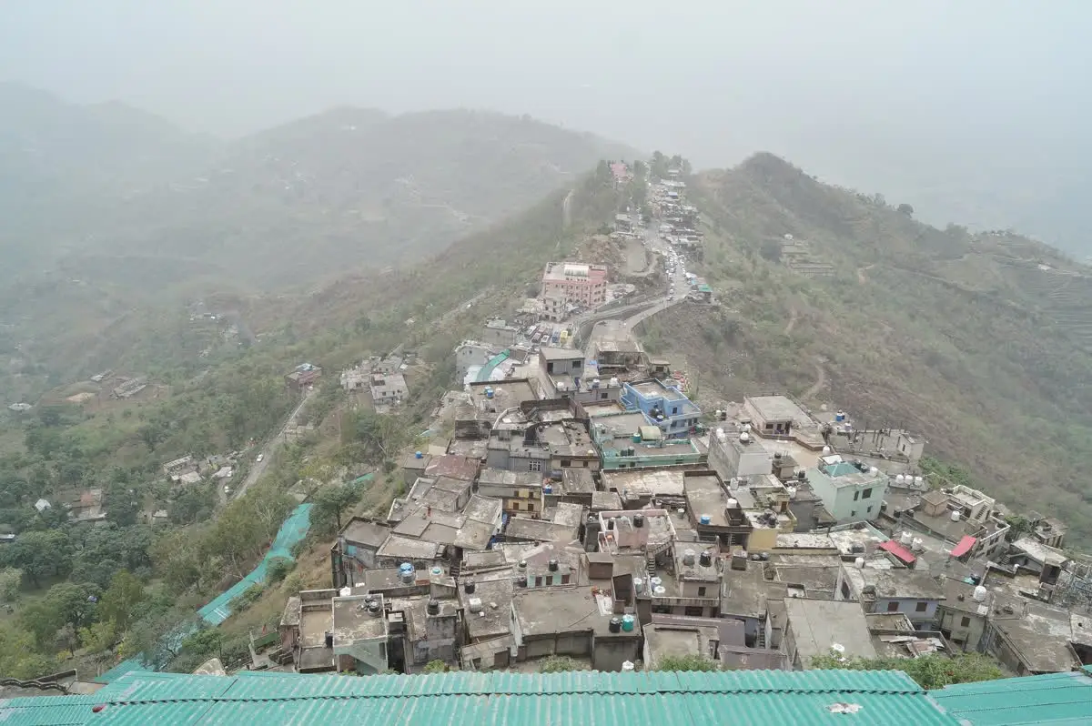 Houses of Naina Devi town packed along a hazy mountain ridge in Himachal Pradesh