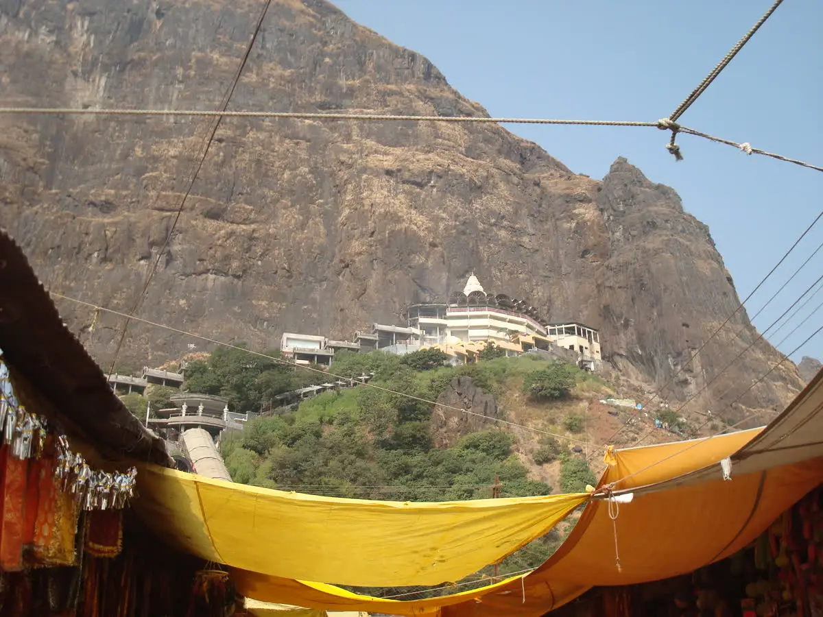 Saptashrungi temple on the hillside seen from below, past shop awnings at Vani