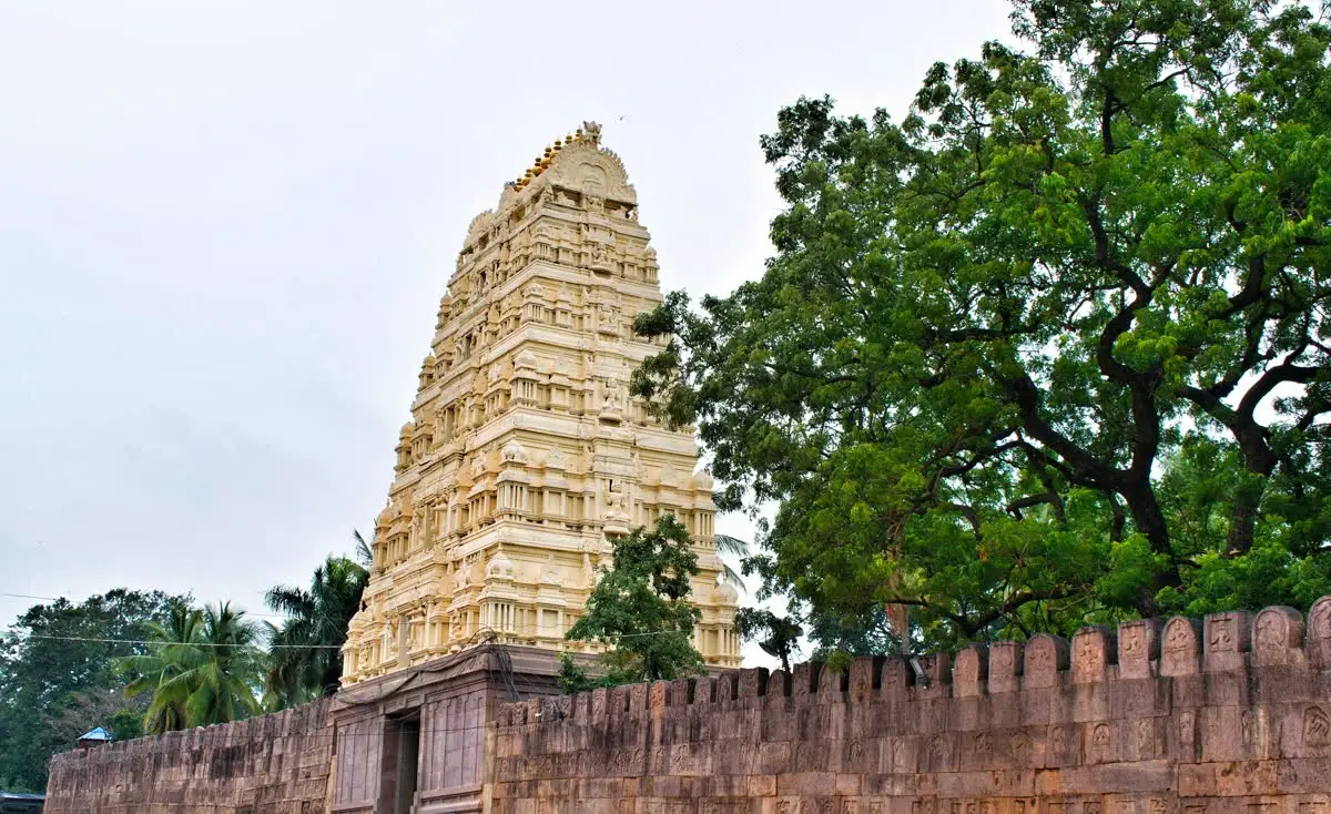 Cream-coloured gopuram rising above the stone compound wall of Srisailam Mallikarjuna temple