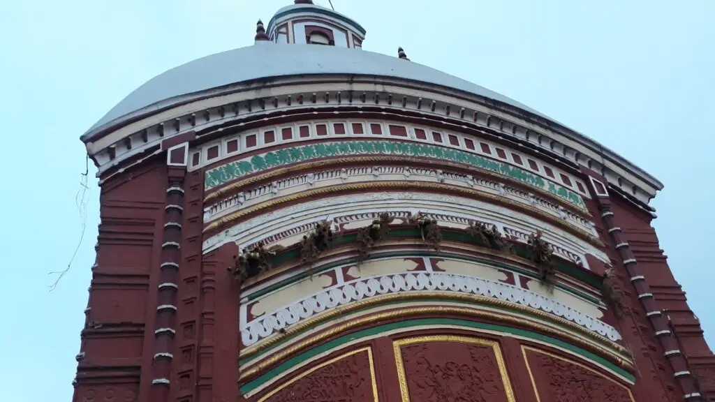 Red terracotta facade and white dome of the Tarapith Tara temple with pilgrims gathered below