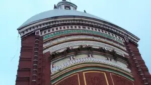 Red terracotta facade and white dome of the Tarapith Tara temple with pilgrims gathered below