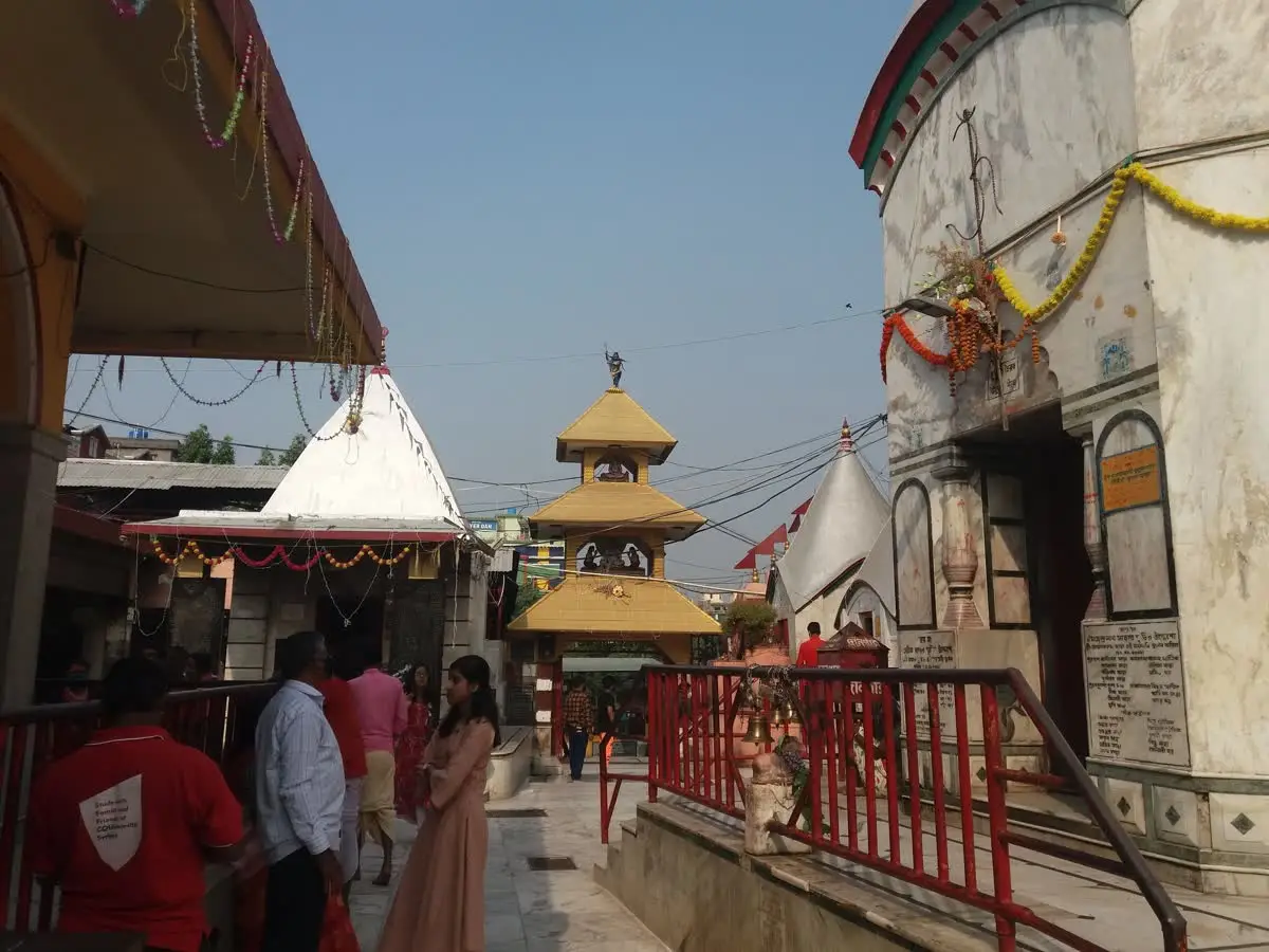 Garlanded white temple dome and small shrines with a golden pagoda spire in the Tarapith complex