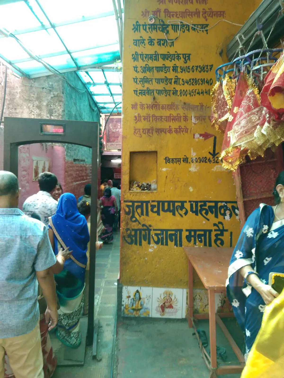 Pilgrims entering the covered passage at the Vindhyavasini temple, with a no-footwear notice